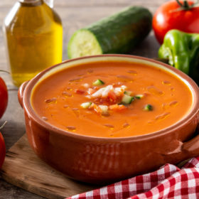 Gazpacho soup in crock pot and ingredient on wooden table